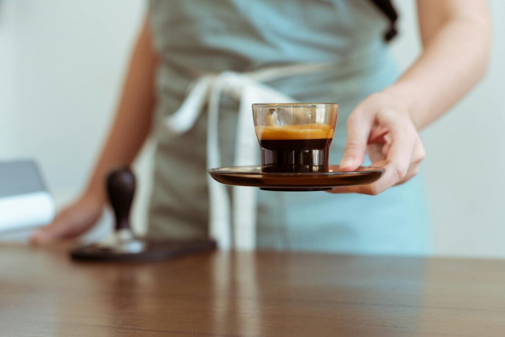 A barista serves a fresh espresso in a modern café. Perfect for coffee lovers.